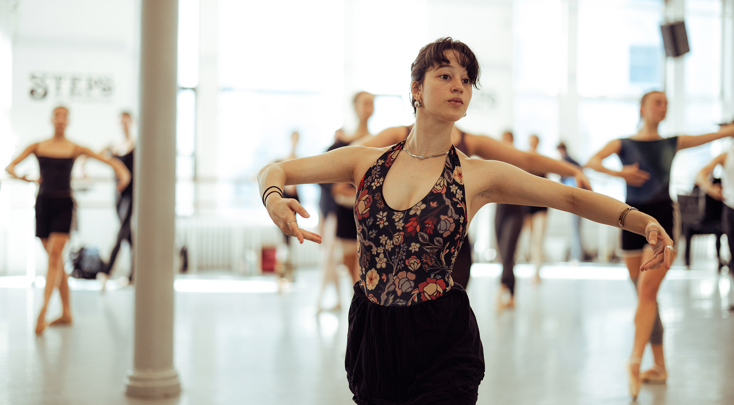 A ballet teacher in the midst of class in a bright dance studio
