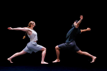Galllim dance in performace, 2 dancers facing each other on a dark stage