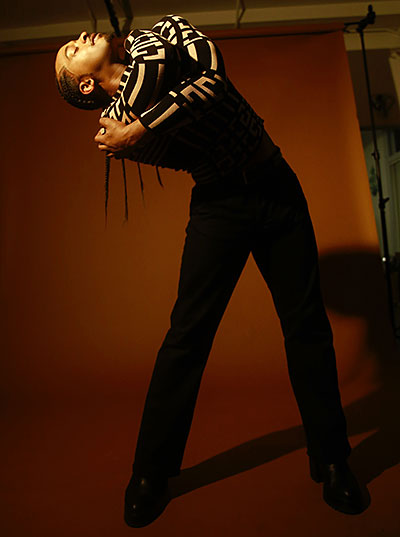 photo of Brandon O'Neal dancing in dark clothes in front of an orange photo backdrop