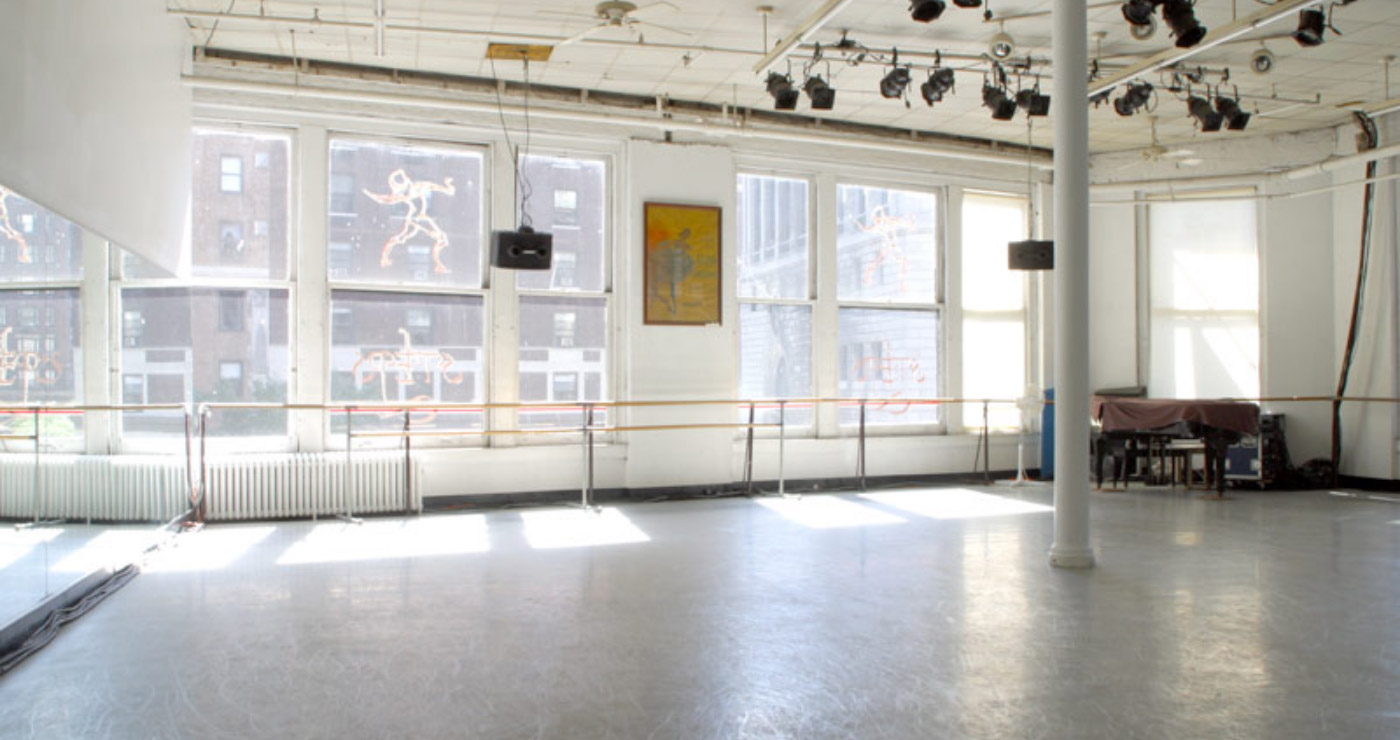 Photo of a large empty dance studio at Steps - with soaring windows, a wall of mirror and a piano