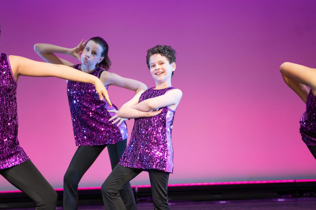 Steps Academy dancers on stage in purple sequined tops and black jazz pants
