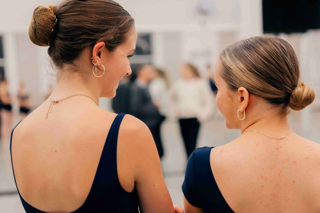 Two academy dancers up close from behind discussing dance