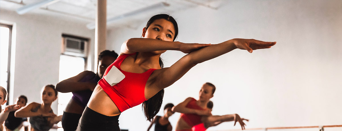 Pre-Professional Dance Student in red leotard, arms stretched out to her side
