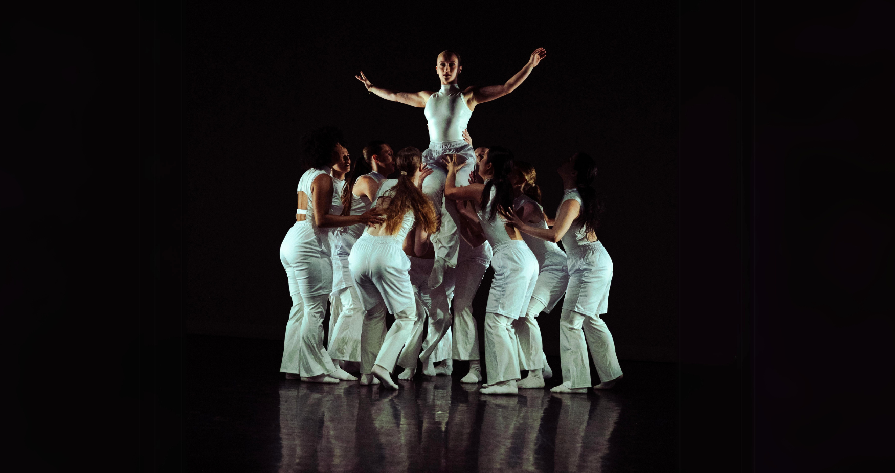 Steps on Broadway dancers on stage in white jump suits lifting one dancer above the others while in a tight circle